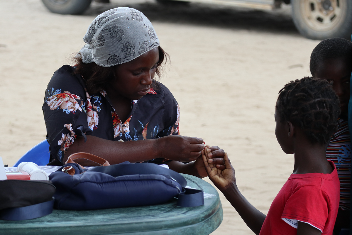 Un'agente comunitaria cura due bambini nei progetti di Medicus Mundi Italia